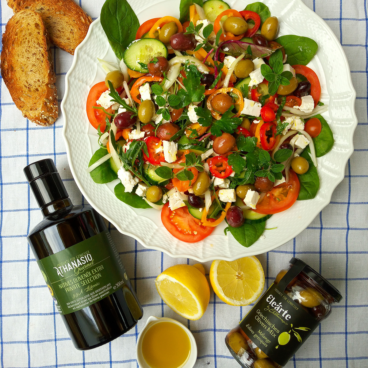 Griechischer Bauernsalat mit frischem Gemüse, Feta, Elearte by Athanasio Griechischer Oliven Mix und Nativem Olivenöl extra auf Servierplatte.